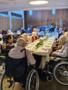 Beim Gründonnerstag-Gottesdienst im Hufeland-Haus sitzen Bewohner*innen und Angehörige zur Erinnerung an das letzte Abendmahl Jesu an schön geschmückten Tischen